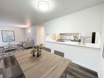 A living room and dining room with a table and a kitchen